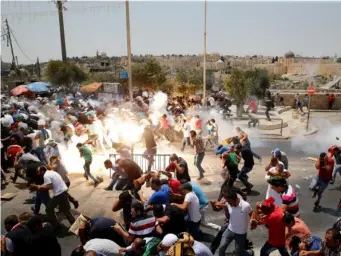  ??  ?? Palestinia­ns react following tear gas that was shot by Israeli forces after Friday prayer on a street outside Jerusalem's Old City (Reuters/Ammar Awad)