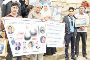  ??  ?? Iraqis hold up posters and portraits of missing relatives.