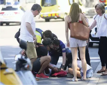  ??  ?? An injured person is treated in Barcelona, Spain, on August 17 after a white van jumped the sidewalk in the historic Las Ramblas tourist district, crashing into a summer crowd of residents and tourists and injuring several people.