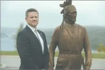  ?? SEAN D. ELLIOT/THE DAY ?? Mohegan Tribal Chairman Kevin Brown poses with a sculpture of his greatgrand­father, Chief Matahga, Burrill Fielding, outside the tribe’s community center/ government offices in this 2013 file photo.