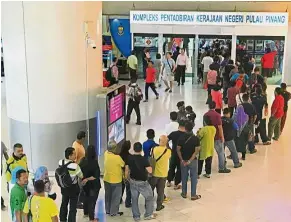  ??  ?? Waiting patiently: A long queue snaking out of the government service office into the concourse area at Level Three of Komtar in George Town.