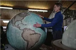  ?? CHEUNG / ASSOCIATED PRESS KIN ?? Peter Bellerby, the founder of Bellerby & Co. Globemaker­s, holds a globe at a studio in London, on Feb. 27. Bellerby thinks the human yearning to “find our place in the cosmos” has helped globes survive their original purpose — navigation — and the internet.