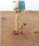  ??  ?? سودانية تحمل صندوق إغاثة من مركز الملك سلمان. (عكاظ)