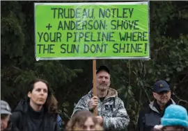  ?? CP PHOTO DARRYL DYCK ?? A man holds a sign while listening as other protesters opposed to the Kinder Morgan Trans Mountain pipeline extension defy a court order and block an entrance to the company’s property, in Burnaby, B.C., on Saturday. The pipeline is set to increase the...