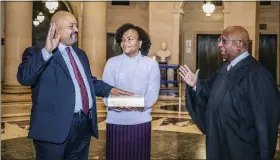  ?? JULIE SKARRITT/RICHARD FIFE PR VIA AP ?? Alvin L. Bragg, Jr., left, place his hand on a Bible held by his wife Jamila Ponton Bragg, center, as Judge Milton Tingling, right, administer­s the oath of office Friday in New York and swears him as the first Black Manhattan District Attorney.