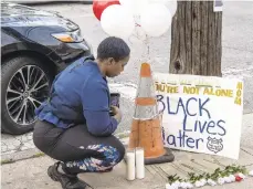  ??  ?? A neighbor gathers at a memorial outside Walter Wallace Jr.’s home.