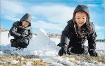  ??  ?? Tenley Chou, 5, right, reaches for a pile of snow to build her snowman with brother Jace Chou, 7, Monday at Fox Hill Park.