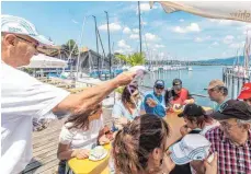  ?? FOTO: CHRISTIAN FLEMMING ?? Achim Holz vom LSC überreicht den Segelgäste­n die beliebten „Rund um“Kappen als Erinnerung an ihren ersten Segeltörn.