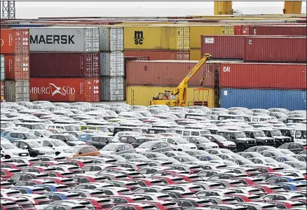  ??  ?? In this file photo, cars for export and import are stored in front of containers at the harbor in Bremerhave­n, Germany. The German economy shrank by 0.1
percent in the second quarter as global trade conflicts and troubles in the auto industry weighed on Europe’s largest economy. (AP)