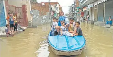  ?? SANJEEV KUMAR/HT ?? Vijay Kumar, a former councillor, along with children boating on a flooded road after heavy rain at Parsram Nagar locality in Bathinda on Tuesday.