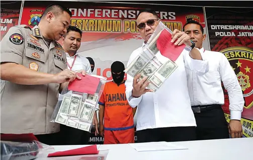  ?? GUSLAN GUMILANG/JAWA POS ?? SALAH JUALAN: Kombespol R. Pitra Andrias Ratulangie (kanan) menunjukka­n barang bukti dolar palsu di Mapolda Jatim kemarin.