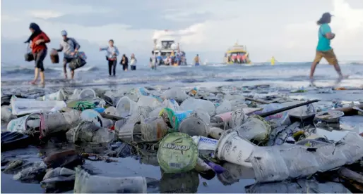  ?? Reuters ?? Tourists and local residents disembark a boat coming from nearby Nusa Penida island as plastic trash pollutes the beach in Bali, Indonesia. —