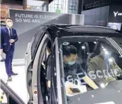  ?? NG HAN GUAN/AP ?? A man stands by as two people check out the all-electric Volvo XC40 in April in Shanghai, China. Volvo is planning to offer only electric vehicles by 2030.