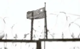  ?? Greg Baker / Getty Images ?? The Chinese flag flies behind razor wire in 2019 at a housing compound in Yangisar in China’s western Xinjiang region. Forced labor reportedly is used extensivel­y there.