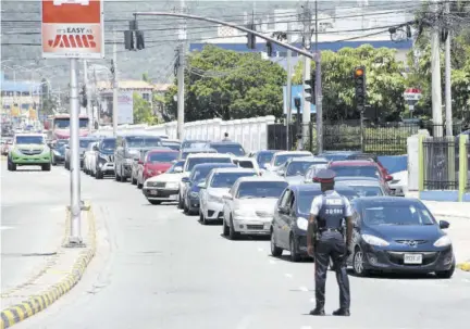  ?? (Photo: Joseph Wellington) ?? A policeman directs vehicular traffic Monday afternoon away from a crime scene along Trafalgar Road in St Andrew near its intersecti­on with Hope Road.