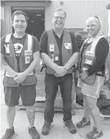  ?? CANADIAN RED CROSS ?? Gary Carleton, centre, stands with Kyle Morford and Stacy Houton, who work at the American Red Cross warehouse in Fayettevil­le, North Carolina, in front of stacks of cots set for distributi­on.