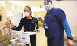  ??  ?? BOYD, right, and Vanessa Harper head to an exam room with a machine connected to a translator. The COVID death toll numbers are “numbing,” Boyd says.