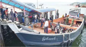  ?? — Reuters ?? A group of Myanmar migrant workers cross the border between Thailand and Myanmar by boat near the Thai port city of Ranong on Monday.