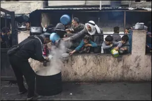  ?? ASSOCIATED PRESS ?? Palestinia­ns line up for a free meal Friday in Rafah, Gaza Strip. Internatio­nal aid agencies say Gaza is suffering from shortages of food, medicine and other basic supplies as a result of the war between Israel and Hamas.