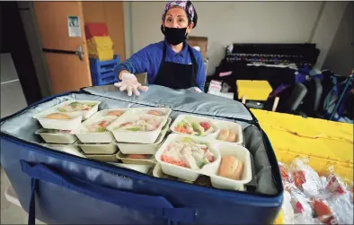  ?? Erik Trautmann / Hearst Connecticu­t Media ?? Ayala Cossio of Chartwells readies meals for pickup at Norwalk Public Schools’ meal-distributi­on site at Brien McMahon High School in Norwalk Tuesday. Below, J.J. Santamaria, 5, at the distributi­on site at Colonial Village.