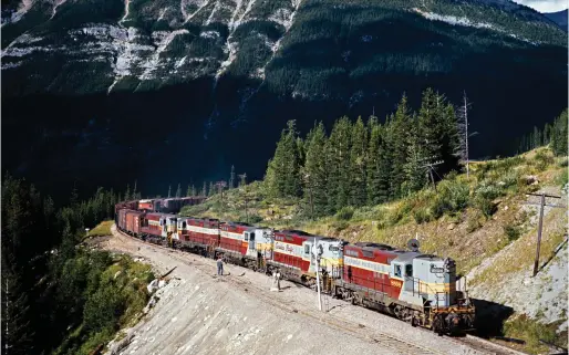  ?? ?? Freight trains meet at the west end of the siding at Cathedral on Aug. 17, 1966. You can see the van (Canadian parlance for a caboose) of the eastward train about to go around the curve, while a quartet of GP9s and a single Fairbanks-Morse unit lead the westward consist.