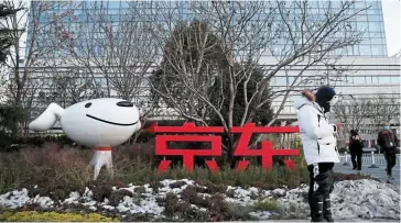  ?? — Reuters ?? All set: A man stands outside Jd.com’s headquarte­rs in Beijing. The company will kick off the online shopping festival today and offer discounts and shopping coupons.