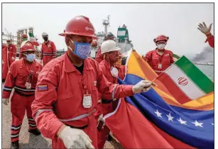  ?? (AP/Ernesto Vargas) ?? A Venezuelan oil worker holds up a small Iranian flag during a ceremony Monday for the oil tanker’s arrival at the El Palito refinery near Puerto Cabello, Venezuela.