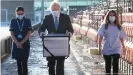  ??  ?? Wenn der Chef persönlich den Impfstoff bringt: Der britische Premier Boris Johnson trägt eine Kühlbox mit dem Astrazenec­a-Vakzin