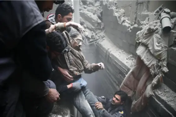  ?? (Reuters) ?? Civil defence rescue workers help a man from a shelter after an air strike in the besieged town of Douma in eastern Ghouta on Thursday