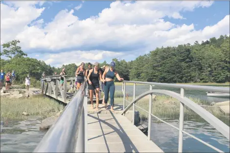  ?? SUBMITTED ?? Katie Spotz, front right, and friends cross a pier at Porter Landing at the end of her run across Maine.