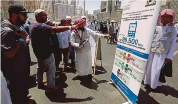  ?? AFP PIC ?? A translator helps pilgrims find informatio­n on a poster displaying helpful smartphone applicatio­ns in Makkah recently.