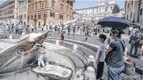  ?? EFE ?? Los turistas se refrescan en la fuente 'Barcaccia' situada en la plaza de España durante la ola de calor, en Roma.