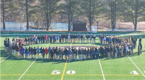  ?? MATT BUTTON/BALTIMORE SUN MEDIA GROUP ?? Students at John Carroll High School in Bel Air gather at the center of the football field to pray against violence in schools and read the names of the Florida shooting victims.