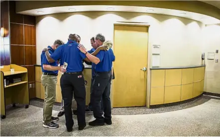  ??  ?? Members of the Billy Graham Rapid Response Team stop to pray with the hospital security guard and a paramedic in the lobby of Sunrise Hospital in Las Vegas. The hospital treated more than 200 patients in the ER the night of the mass shooting.