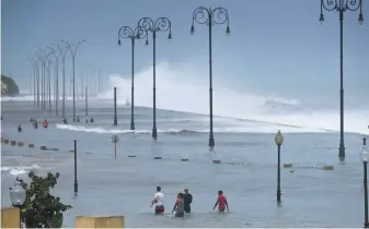  ?? Ramon Espinosa / Associated Press ?? Residents wade through floodwater­s on Havana’s Malecon on Sept. 10 after the passage of Hurricane Irma. The coastal boulevard was built atop coral reefs and mangrove forests.