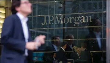  ??  ?? WORKERS ARE REFLECTED in the windows of the Canary Wharf offices of JP Morgan in London.