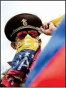  ?? AP/WIL RIERA ?? A Venezuela anti-government protester wears a Russian military hat and covers his face in his country’s flag during a demonstrat­ion Sunday in Caracas.