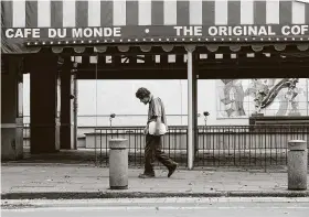  ?? Gerald Herbert / Associated Press ?? A man walks past the closed Cafe Du Monde restaurant on March 27 in the French Quarter of New Orleans. It's normally bustling with tourists.