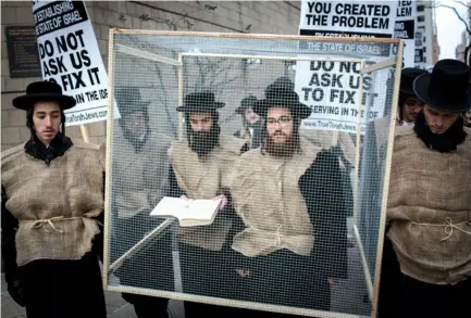  ?? (Reuters) ?? DEMONSTRAT­ORS STAND in a mock prison during a protest by haredi students in New York.