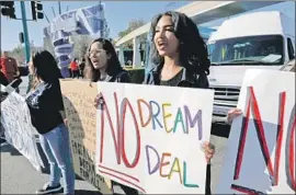  ?? Gary Coronado Los Angeles Times ?? EMILY HEBBARD, center, and her daughter Maxine Hebbard, right, call for protection­s for young immigrants here illegally during a protest at Disneyland.