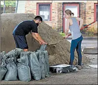  ?? AP/GERALD HERBERT ?? John Flemming and Andrea Dube fill sandbags Friday in New Orleans as the threat of more flooding from rainstorms kept the city on edge. One resident said the potential for flooding and the fear that pumps could be overwhelme­d are “bringing back Katrina...