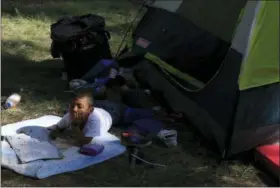  ?? REBECCA BLACKWELL — THE ASSOCIATED PRESS ?? A boy lies with a coloring book outside a tent inside the sports complex where thousands of migrants have been camped out for several days in Mexico City, Friday. About 500 Central American migrants headed out of Mexico City on Friday to embark on the longest and most dangerous leg of their journey to the U.S. border, while thousands more were waiting one day more at a massive improvised shelter.