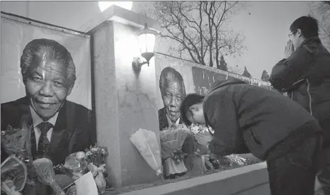  ?? ZOU HONG / CHINA DAILY ?? Two men mourn before portraits of the late Nelson Mandela outside the South African embassy in Beijing on Friday.