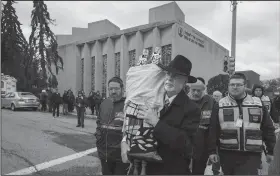  ?? AP/Philadelph­ia Inquirer/CHARLES FOX ?? Rabbi Jeffrey Myers (center) of Tree of Life Synagogue carries the synagogue’s Torah to be stored elsewhere in Pittsburgh on Monday.