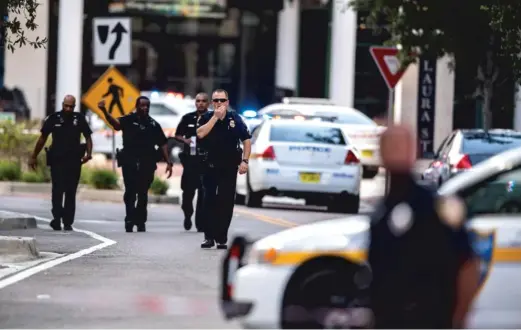  ?? LAURA HEALD/AP (ABOVE); JOHN RAOUX/AP ?? ABOVE: Police gather after an active shooter was reported at the Jacksonvil­le Landing in Jacksonvil­le, Florida, Sunday. A gunman opened fire during an online video game tournament that was being livestream­ed from a mall, killing two people and sending many others to hospitals. LEFT: Florida Highway patrolmen block the entrance to the Main Street Bridge near the scene of the shooting.