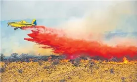  ??  ?? Desde el aire. Aviones hidrantes combaten las llamas en las sierras.