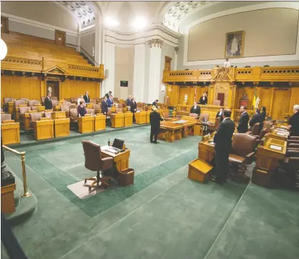  ?? BRANDON HARDER ?? Members of the government and the official opposition stand as Speaker of the Legislativ­e Assembly Mark Docherty enters the chamber on budget day at the Saskatchew­an Legislativ­e Building on Monday. Due to the pandemic, the two parties agreed to limit MLAS in the house.