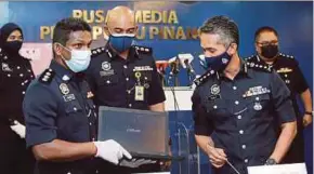  ?? PIC BY MIKAIL ONG ?? Penang police chief Datuk Mohd Shuhaily Mohd Zain (right) and other senior police officers with a laptop seized from the syndicate yesterday.