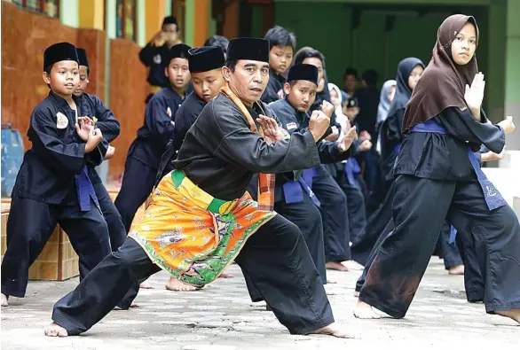  ?? MIFTAHUL HAYAT/JAWA POS ?? TRADISI BELA DIRI: Ketua Dewan Pelatih Perguruan Silat Pusaka Djakarta (PSPD) Memet (tengah) memimpin latihan para siswanya di Ponpes An-Nuriyah, Jagakarsa, Jakarta Selatan, kemarin. Perguruan itu tidak hanya menempa fisik, melainkan juga sisi...