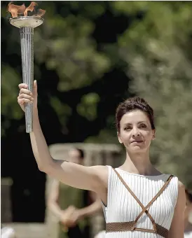  ??  ?? Actress Katerina Lechou acting the high pristess holds a torch with the Olympic flame at the Temple of Hera on Thursday.